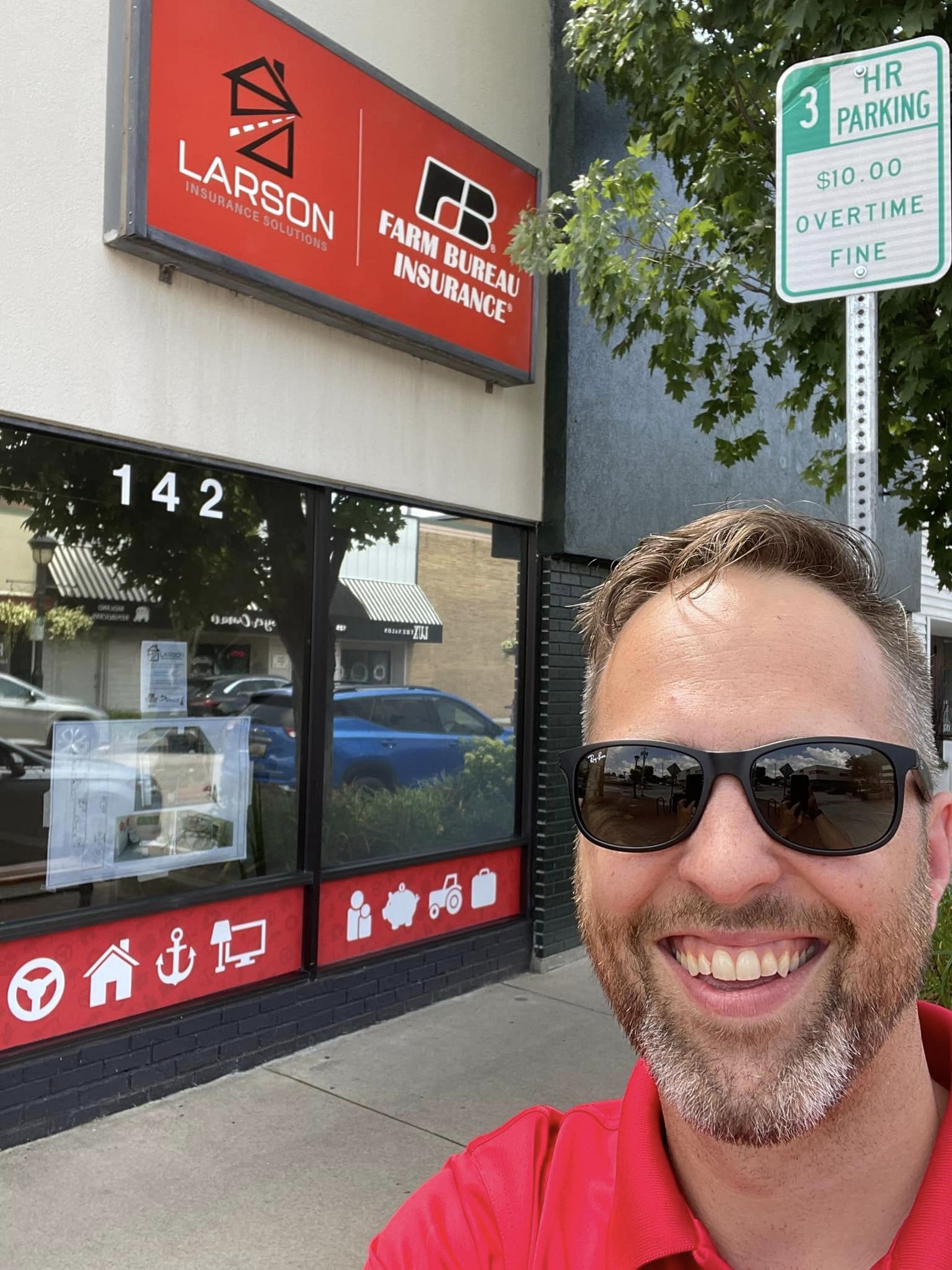 Man smiling in front of Larson Insurance office